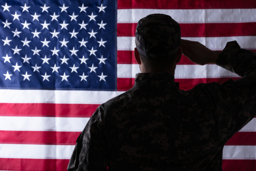 Soldier Saluting American Flag Rearview shutterstock 1369034810